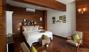 Spacious bedroom with wooden walls, white bedding, and modern furnishings overlooking forest