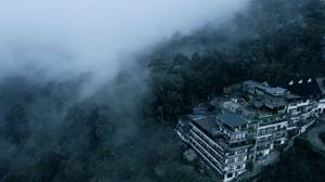 Hotel perched on misty hillside surrounded by lush green forest canopy