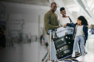 Family with luggage cart checking in at bright hotel lobby area