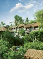 Tropical resort villas with thatched roofs nestled among lush green gardens and palm trees