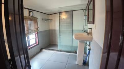 Attached bathroom with a glass-screened shower and a pedestal basin