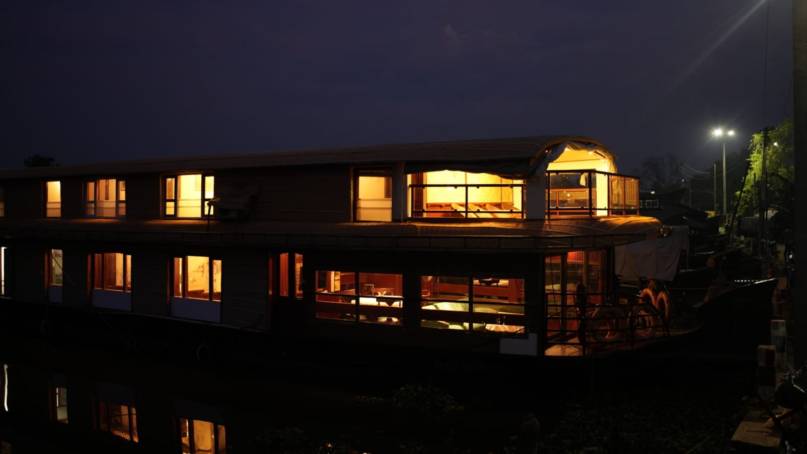 Grand Nirvana, the two-storey houseboat Kerala Escapes runs in Alleppey, lit up at dusk